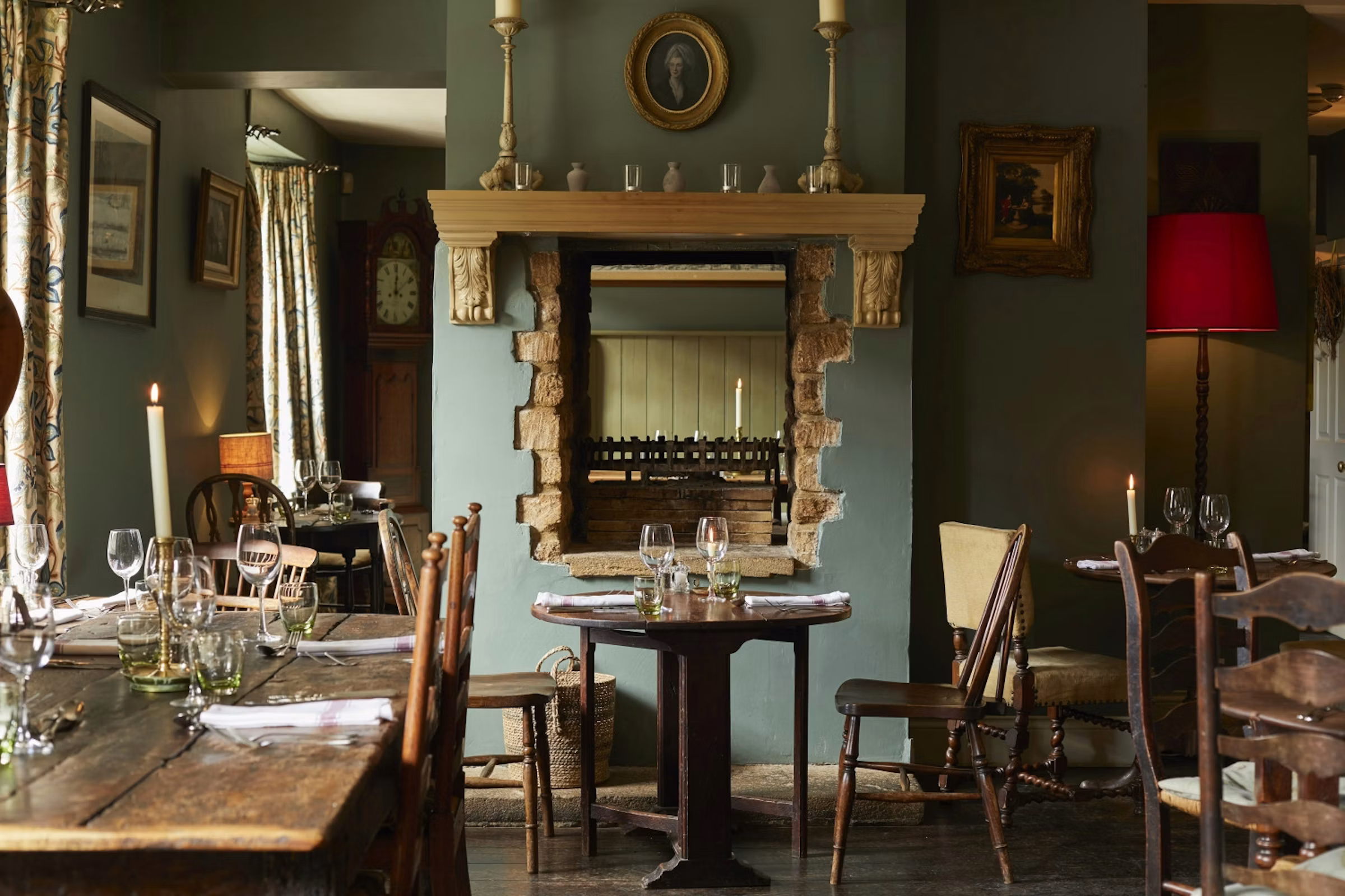 Dining room with a stone fireplace, mirror and candlesticks at the Lord Poulett Arms, Hinton St George